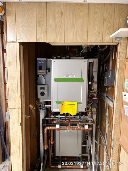 Pride Plumbing, Inc | A boiler is being installed in a room with wood paneling.