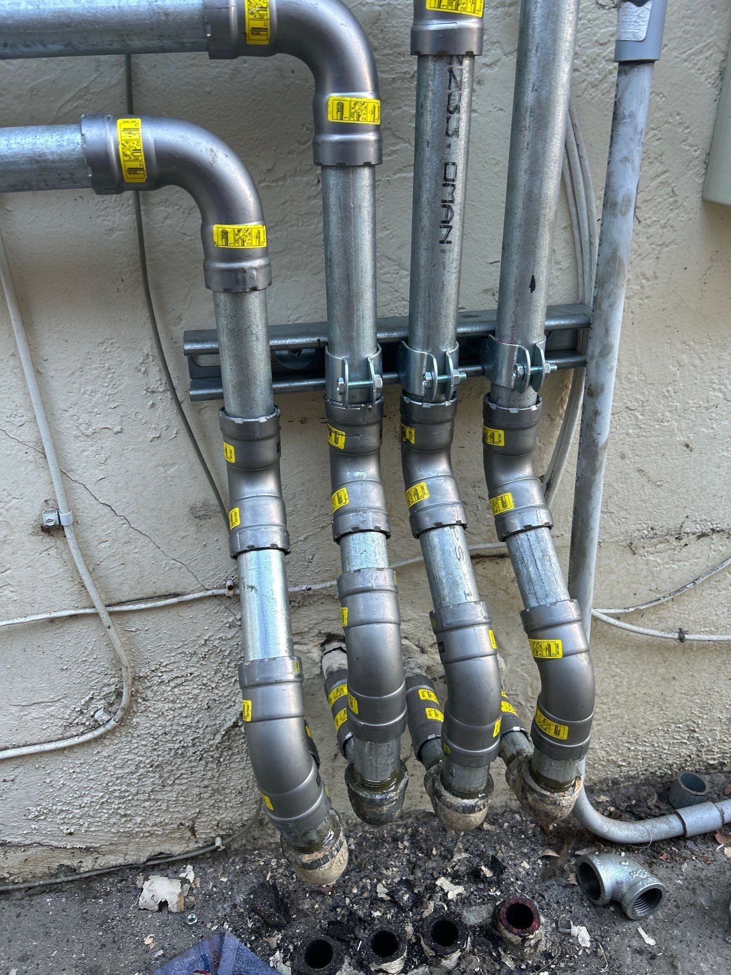 Pride Plumbing, Inc | A bunch of metal pipes are connected to a wall.