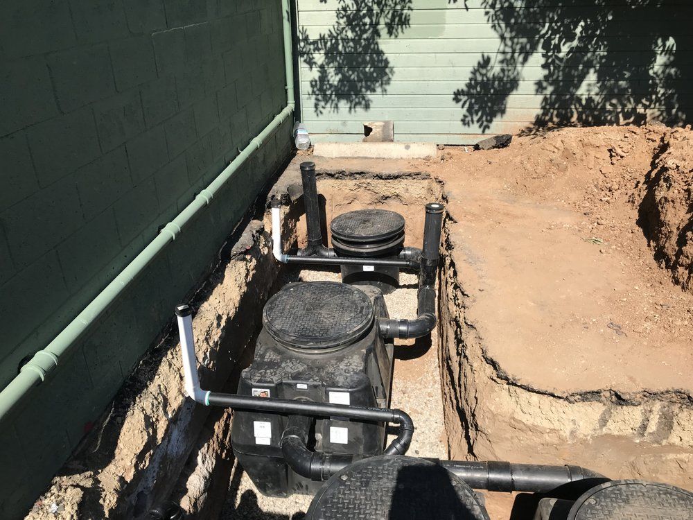 Pride Plumbing, Inc | A septic tank is being installed in the dirt in front of a house.
