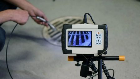 Pride Plumbing, Inc | A man is using a camera to look at a manhole cover.