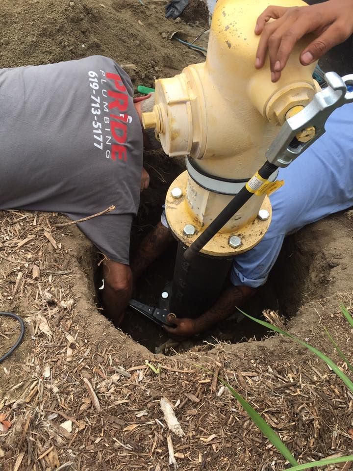 Pride Plumbing, Inc | A man is working on a fire hydrant with a phone number on his back