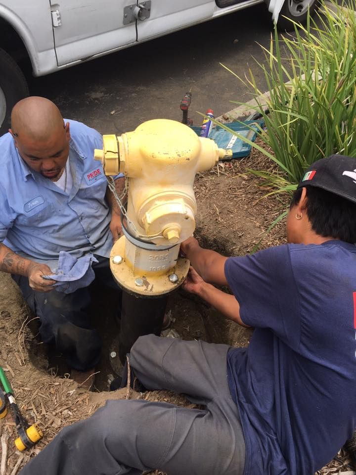 Pride Plumbing, Inc | Two men are working on a yellow fire hydrant