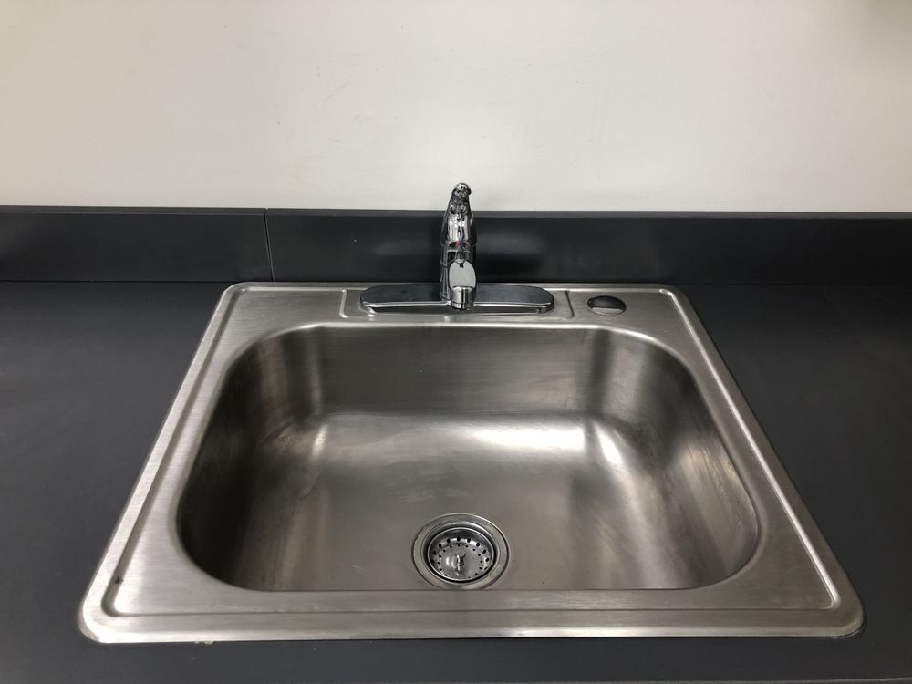 Pride Plumbing, Inc | An empty stainless steel kitchen sink with a faucet