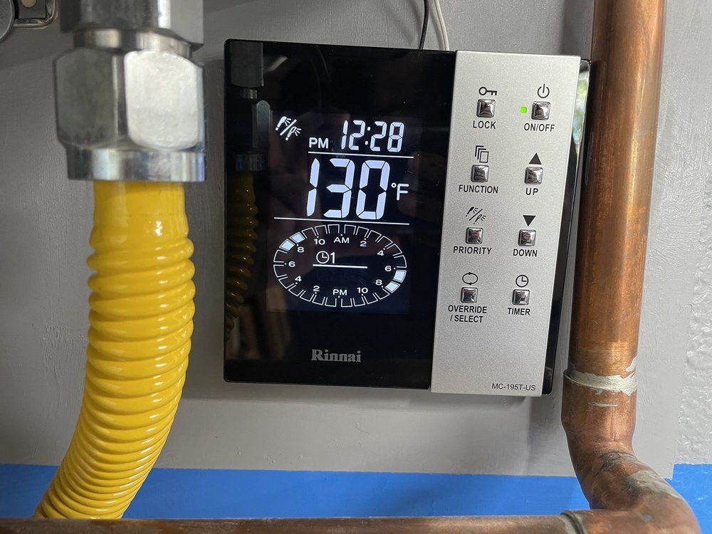 Pride Plumbing, Inc | A gas thermostat is hanging on a wall next to a yellow hose.