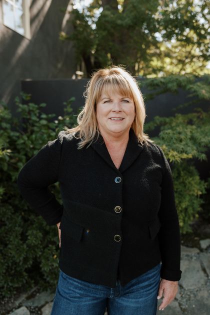 Jenny Smith wearing a black jacket and standing in front of a bush | Real Estate Agent in Greenhaven-Pocket, Sacramento, CA