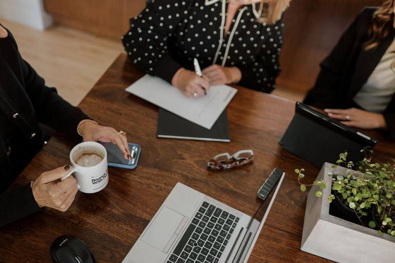 Three women are sitting at a table with a laptop and a cup of coffee | Real estate agent in Greehaven-Pocket, Sacramento, CA