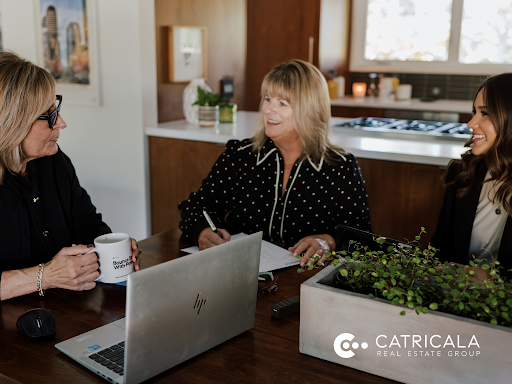 Three women are sitting at a table with a laptop.