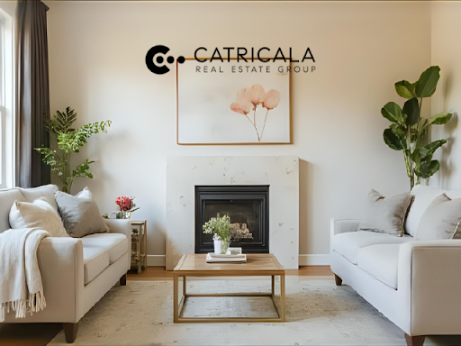 Living room with neutral-toned sofas, fireplace, art, plants, and wood coffee table.