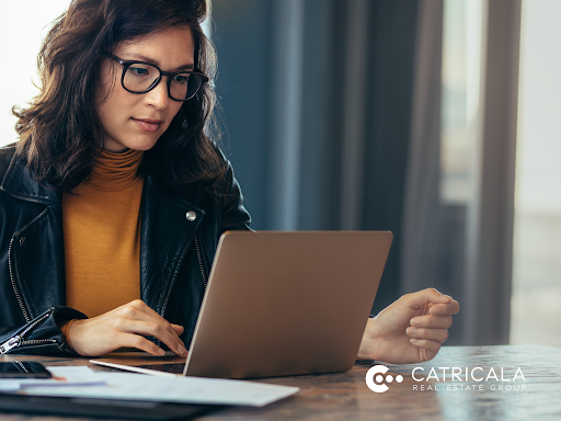 A woman is sitting at a table using a laptop computer.