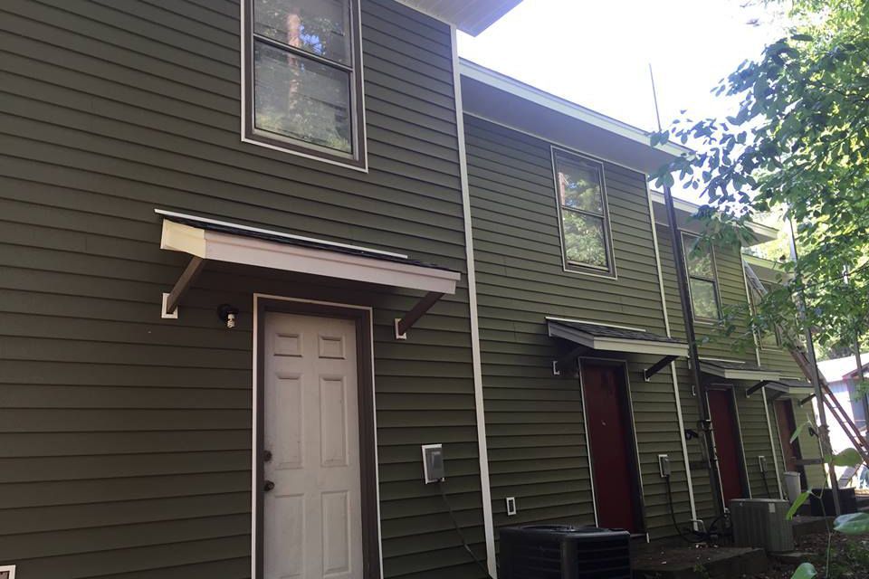 A green house with a white door and a canopy over the door.