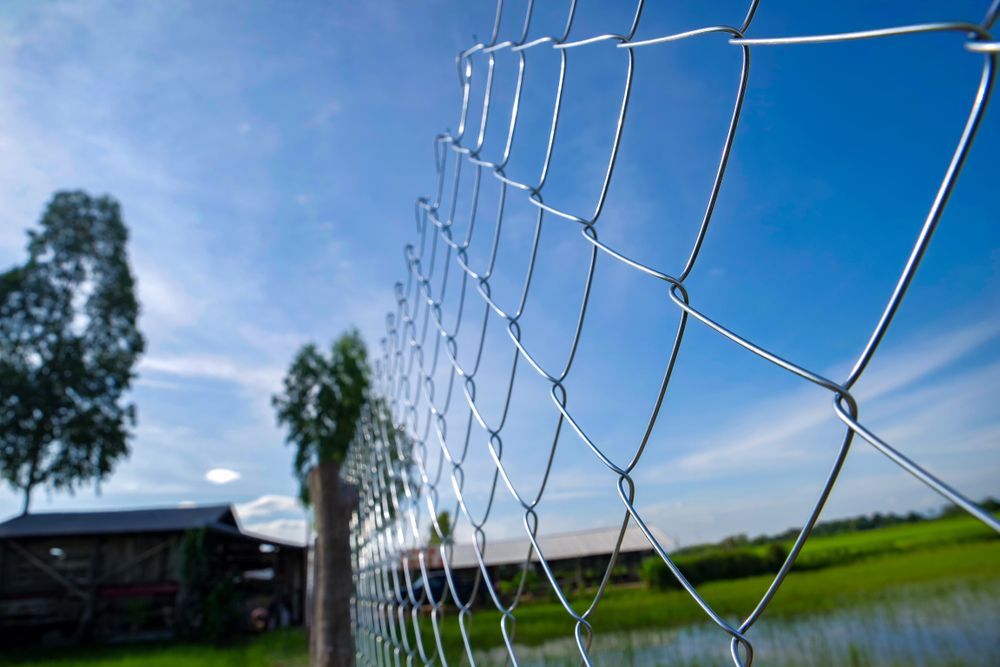 Wire Fence With a Blurred Background of a House — A&H Fences In Mittagong, NSW