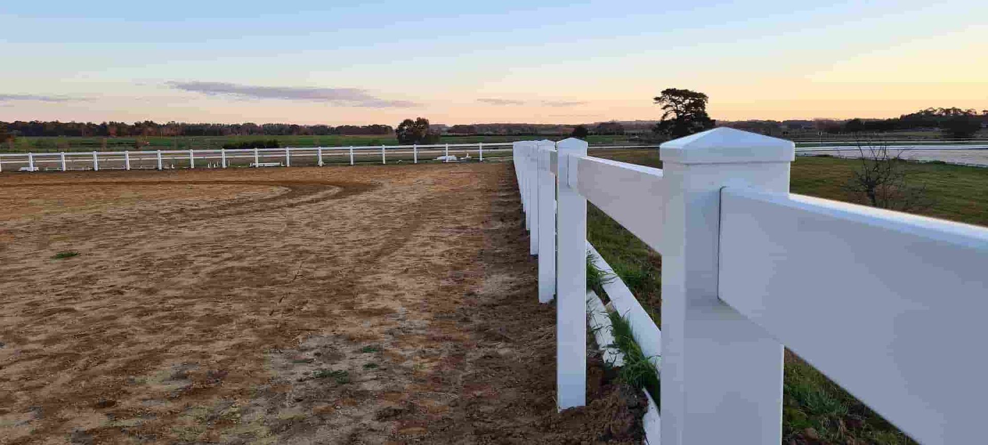 A White Fence Surrounds a Dirt Field — A&H Fences In Bowral, NSW