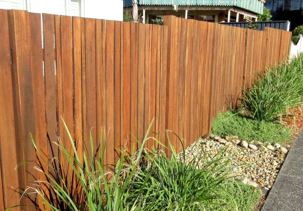 Brown Wooden Fence With Green Bushes in Front — A&H Fences In Aylmerton, NSW
