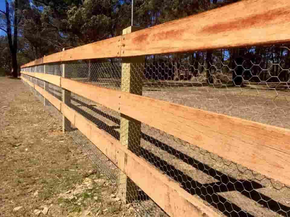 A Wooden Fence With a Chicken Wire Fence Behind It — A&H Fences In Moss Vale, NSW