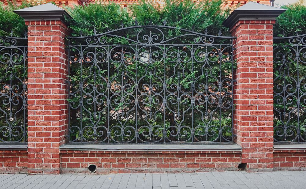 Brick Pillars With Ornate Wrought Iron Fence and Hedge— A&H Fences In Moss Vale, NSW