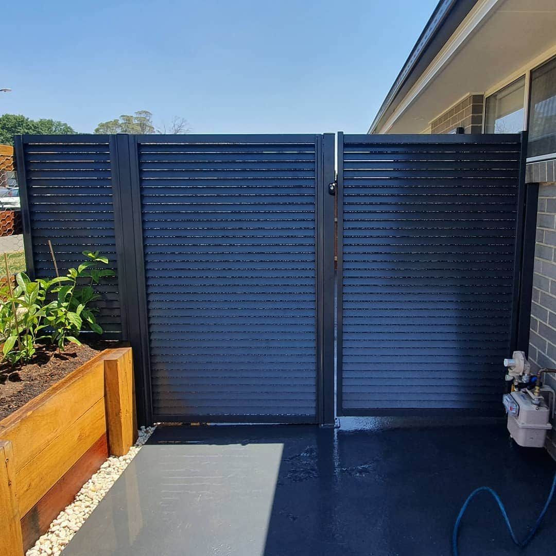 A Black Fence With a Gate in Front of a House — A&H Fences In Mittagong, NSW