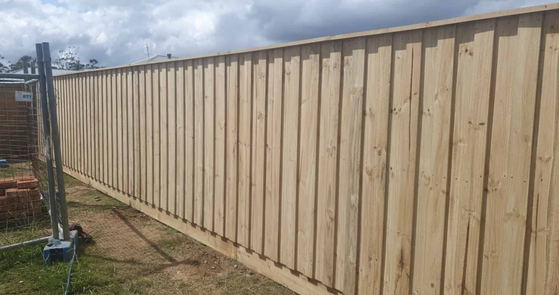 A Wooden Fence is Sitting on Top of a Lush Green Field — A&H Fences In Bowral, NSW