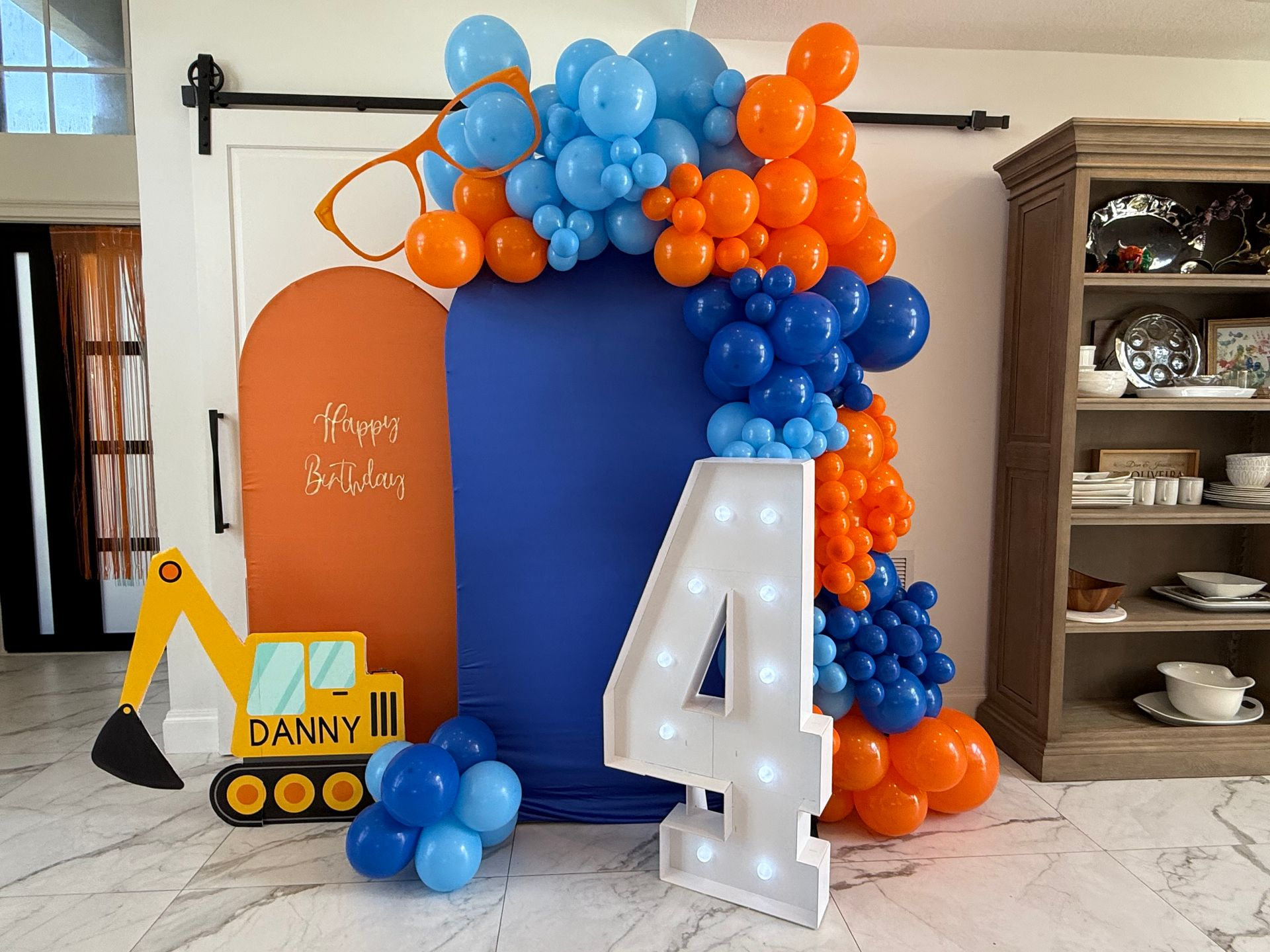 A young boy is holding a bunch of balloons in a living room.