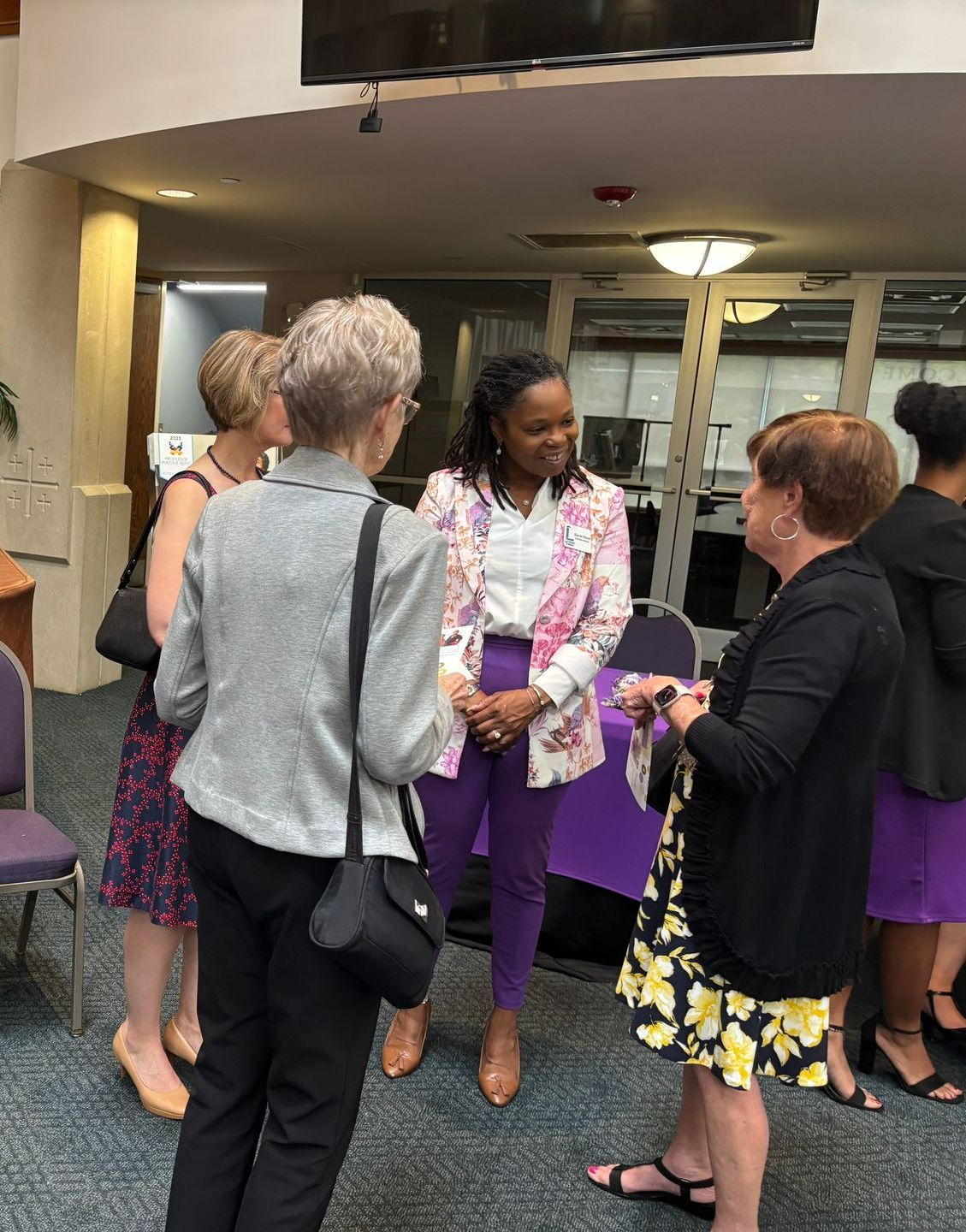 A group of women are standing in a room talking to each other.