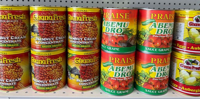 A shelf filled with cans of food including tomatoes and bananas