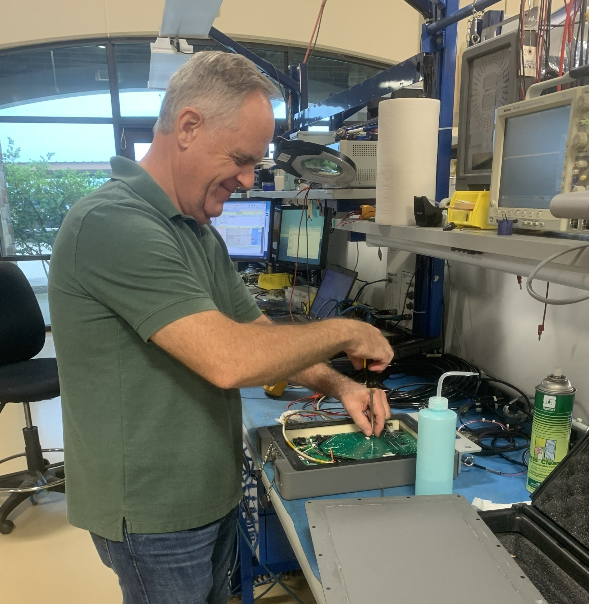 A man in a green shirt is working on a motherboard
