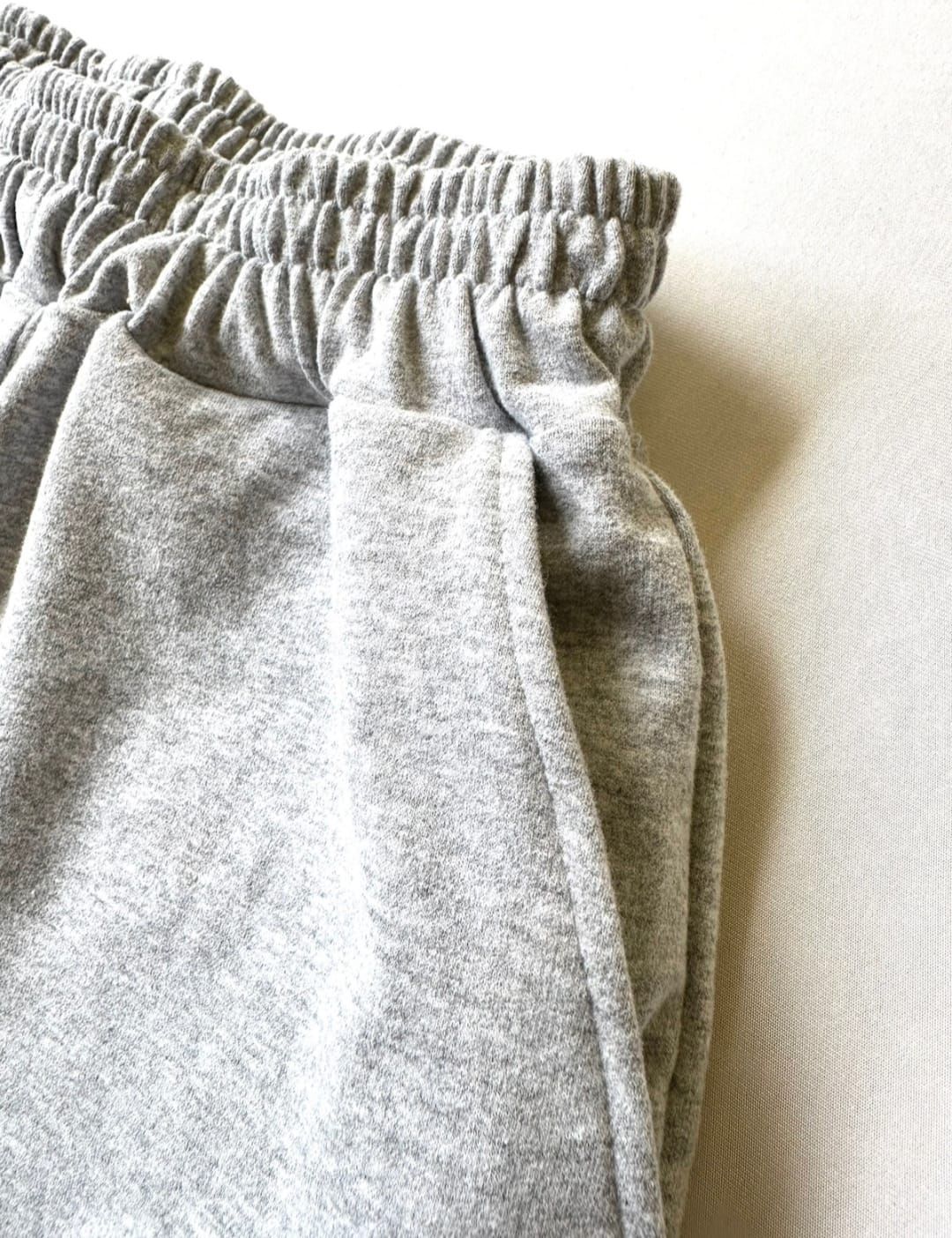 Tres pares de pantalones cortos de jersey, apilados. Negros, grises y tostados, todos con cinturilla elástica.