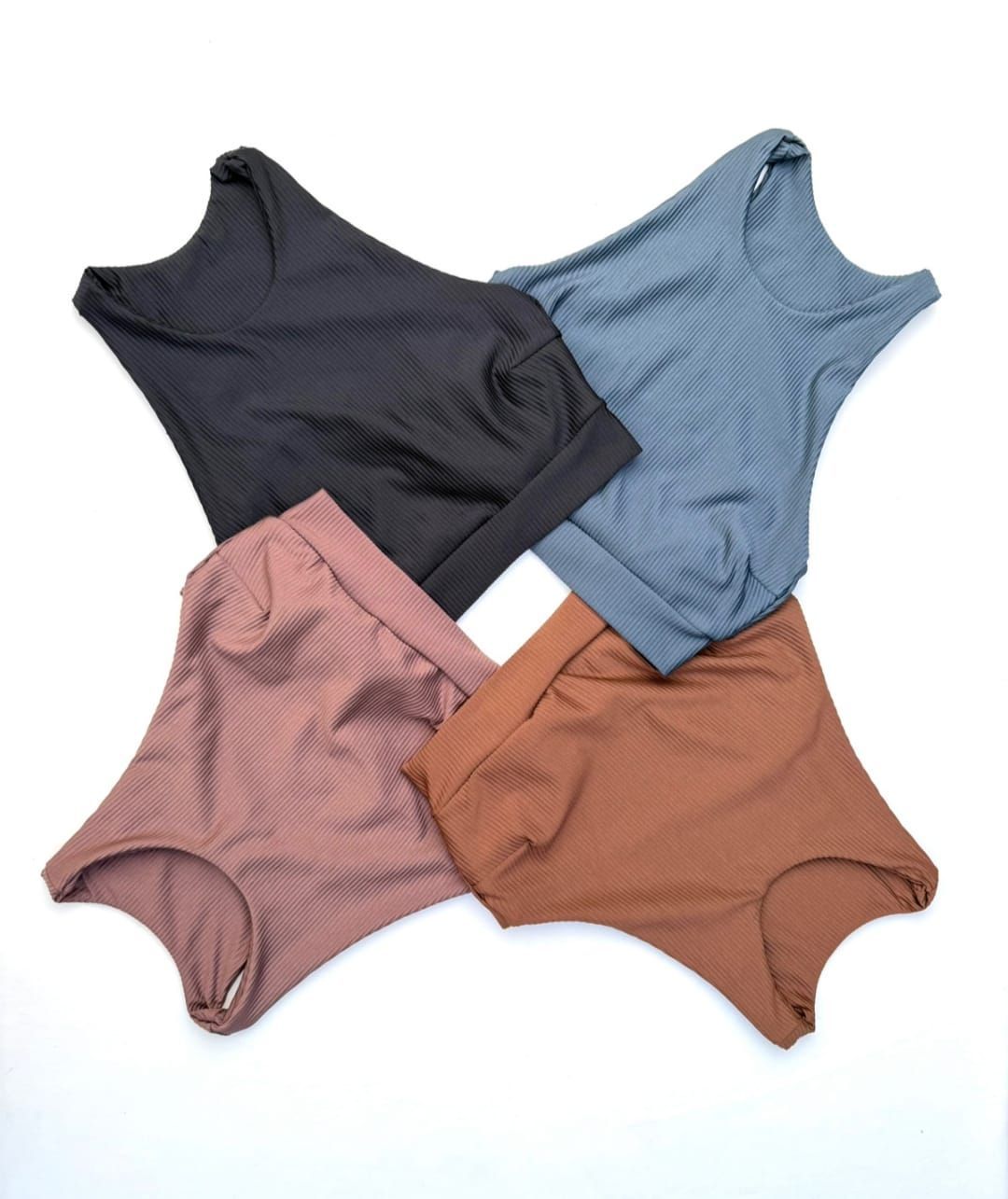 Cuatro tops texturizados con escote redondo y pantalones a juego en negro, azul, malva y marrón, dispuestos en un cuadrado.