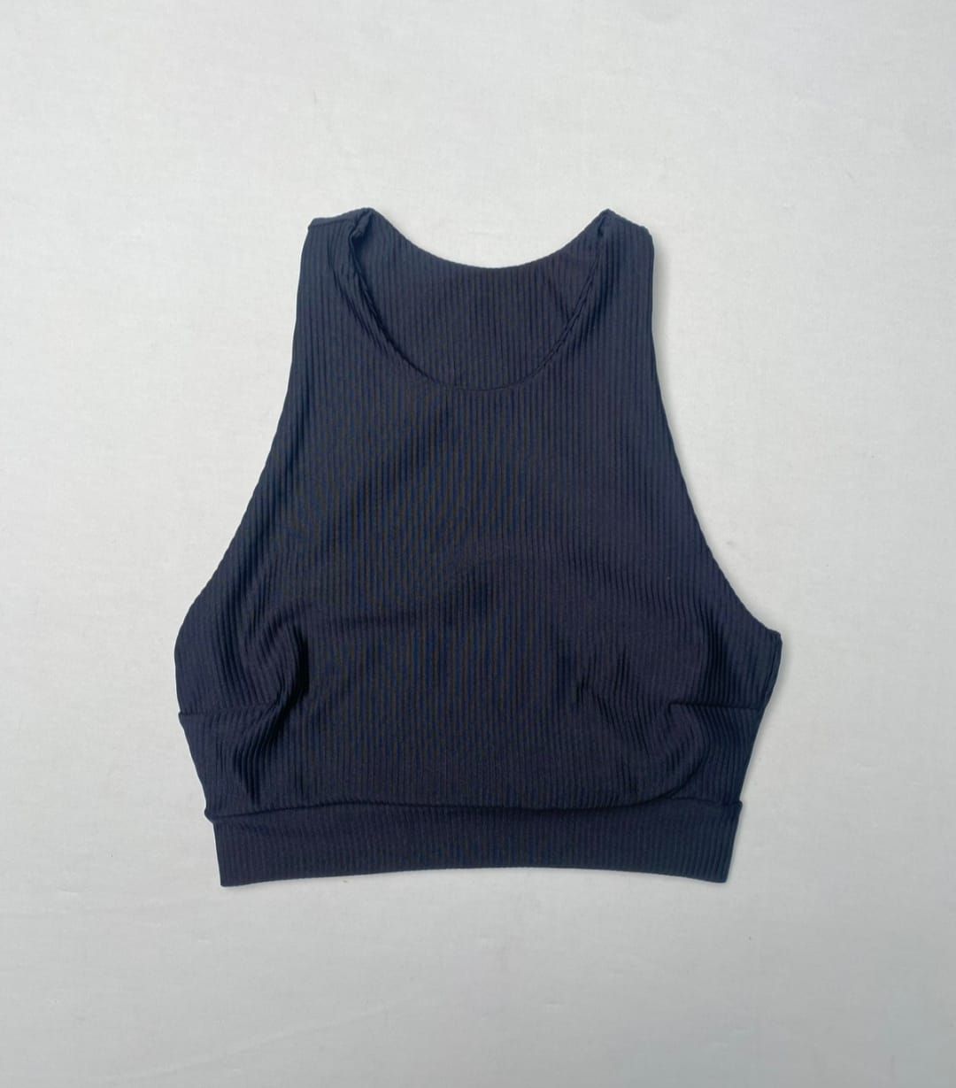 Cuatro tops texturizados con escote redondo y pantalones a juego en negro, azul, malva y marrón, dispuestos en un cuadrado.