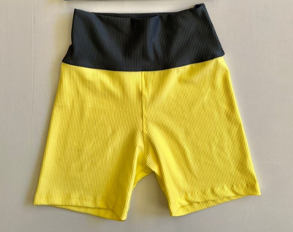 Pantalón corto deportivo de color amarillo y negro con textura acanalada.