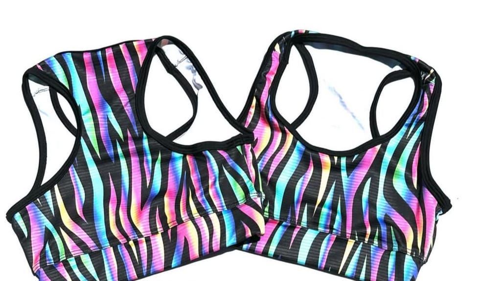 Dos sujetadores deportivos con un colorido estampado de rayas de cebra.