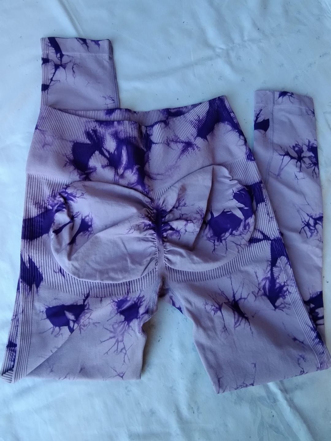 Leggings con estampado tie-dye en tonos morados y lavanda, con detalles fruncidos en la espalda.