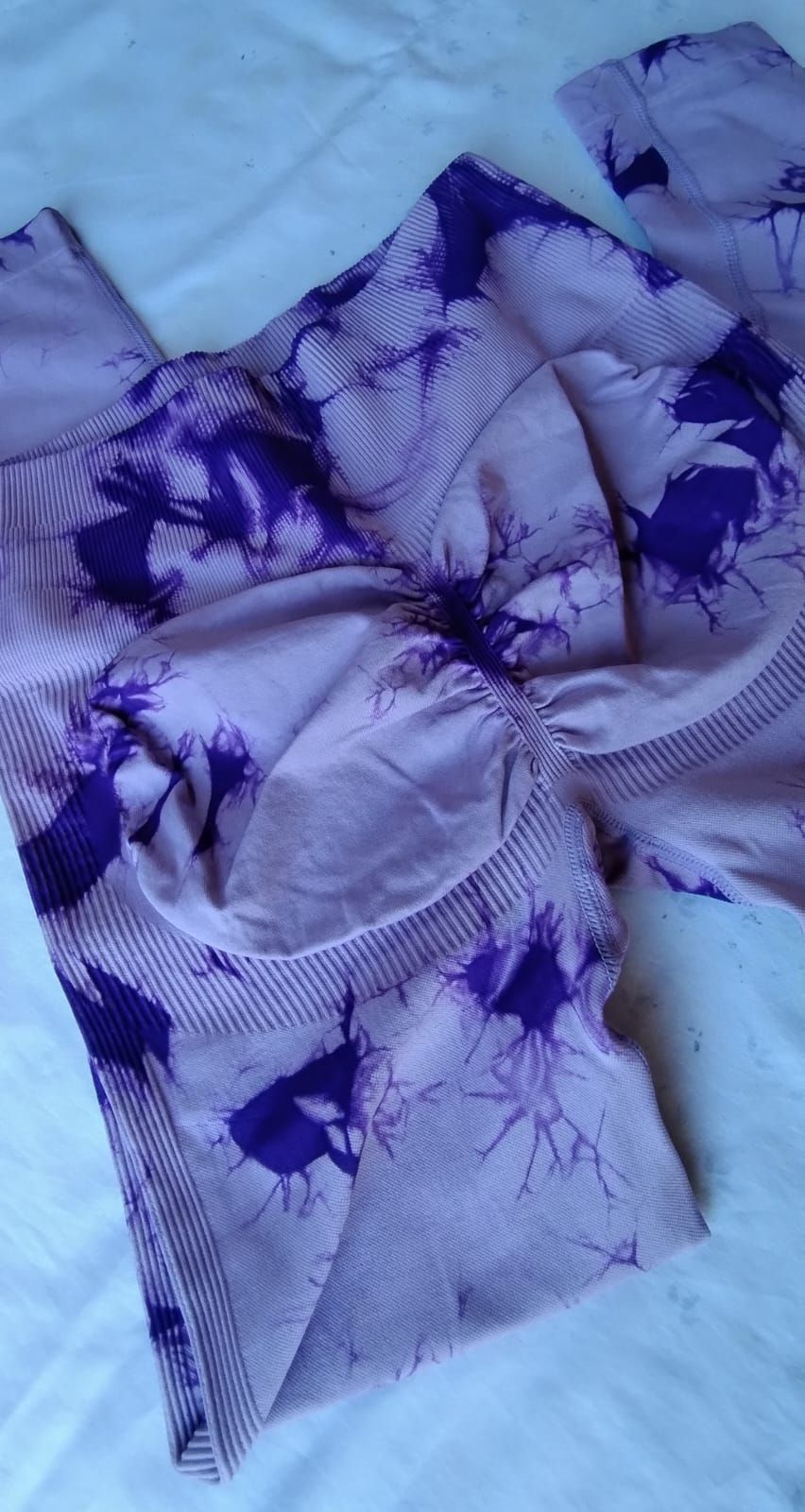Leggings con estampado tie-dye en tonos morados y lavanda, con detalles fruncidos en la espalda.