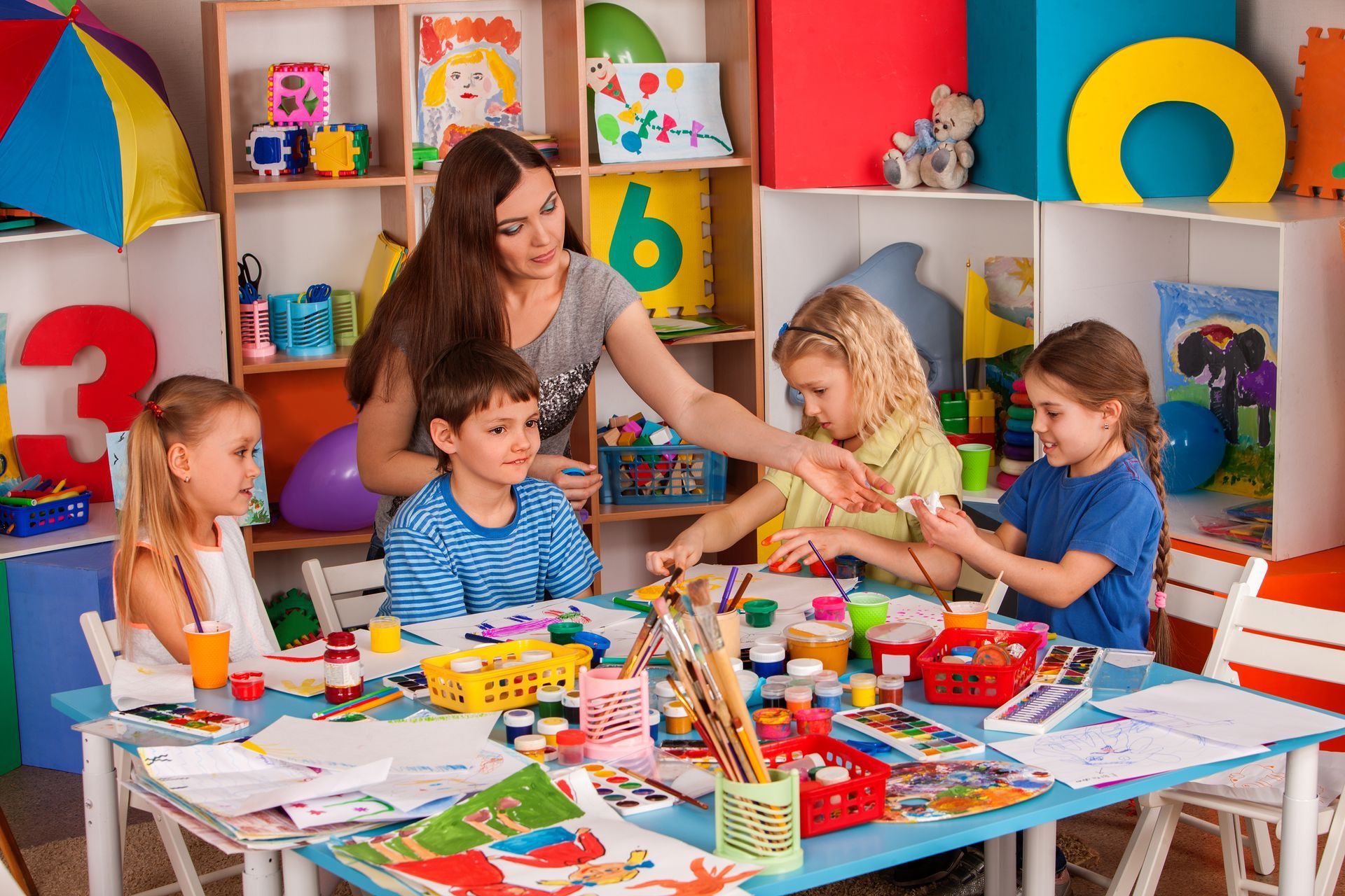 A group of children are sitting at a table with a teacher.