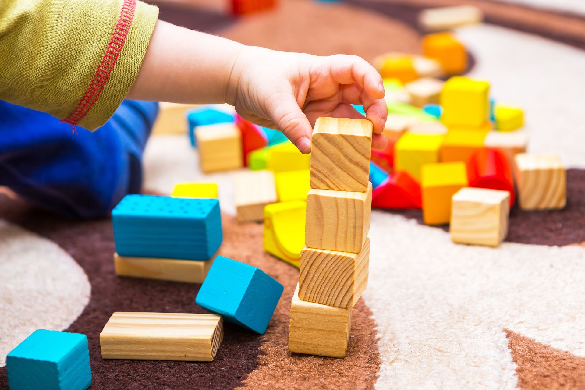 A child is playing with wooden blocks on the floor.