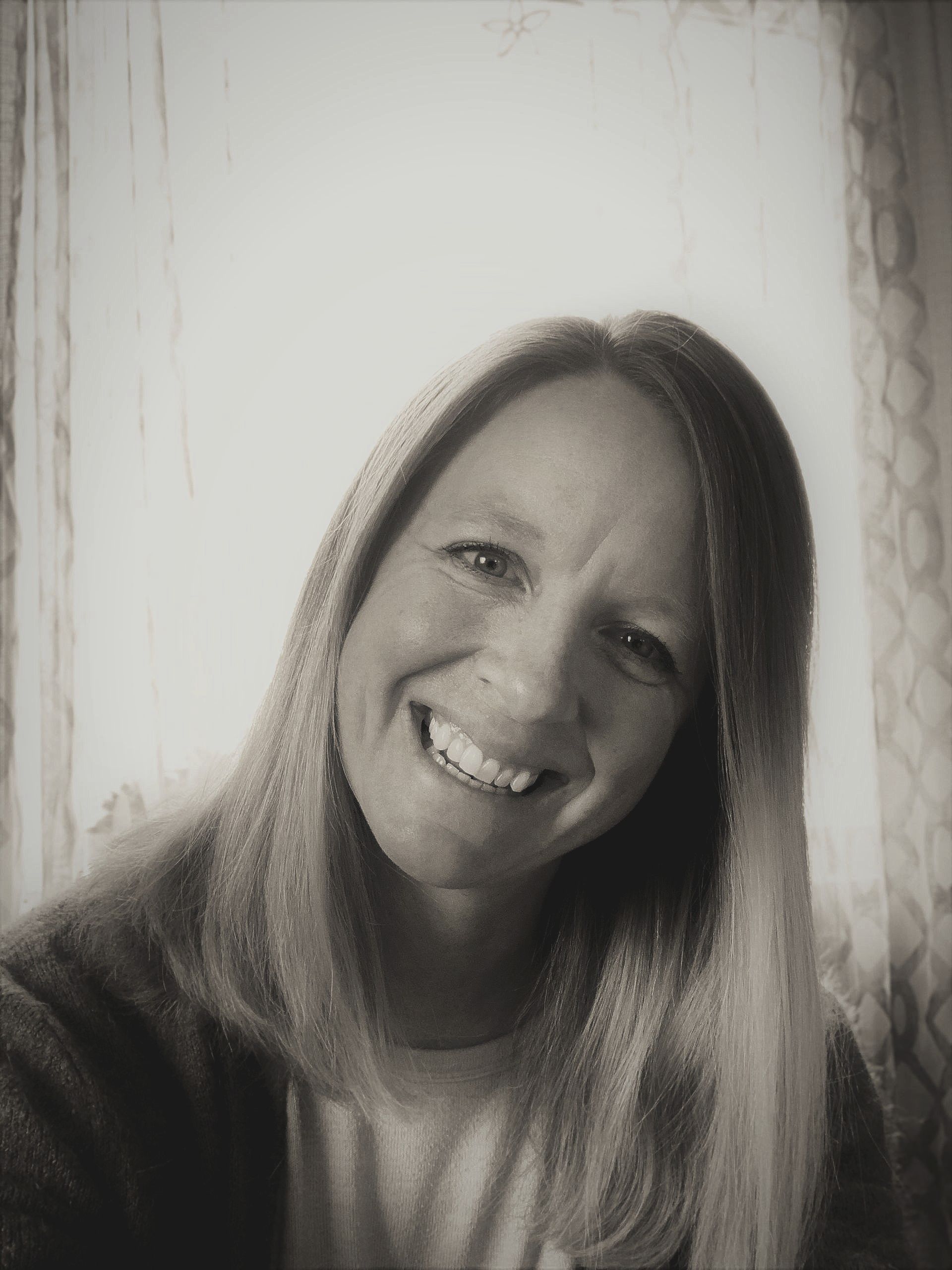 A woman is smiling in a black and white photo.