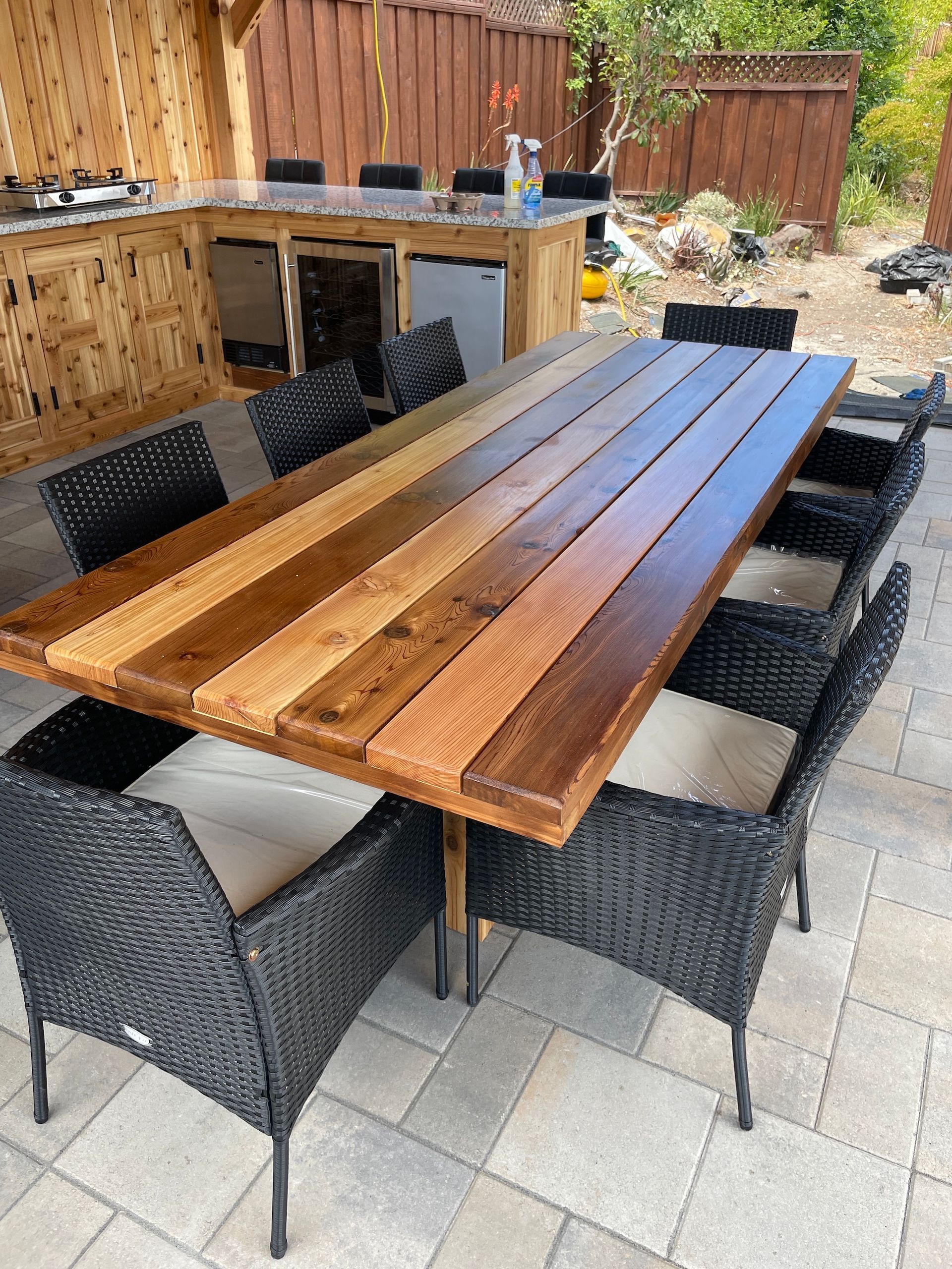 A wooden table with wicker chairs on a patio.