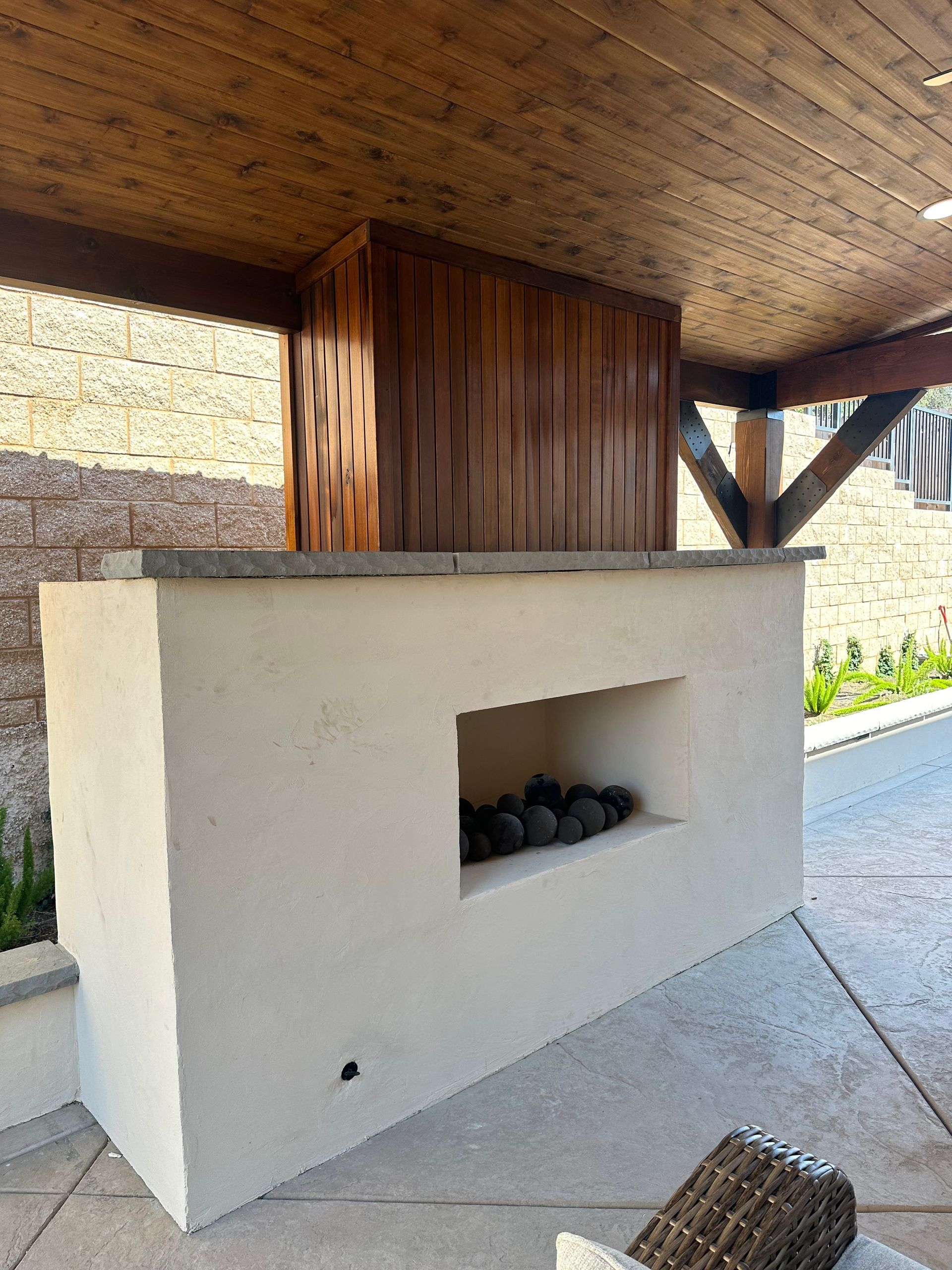 A white fireplace with a wooden ceiling is under a wooden structure.