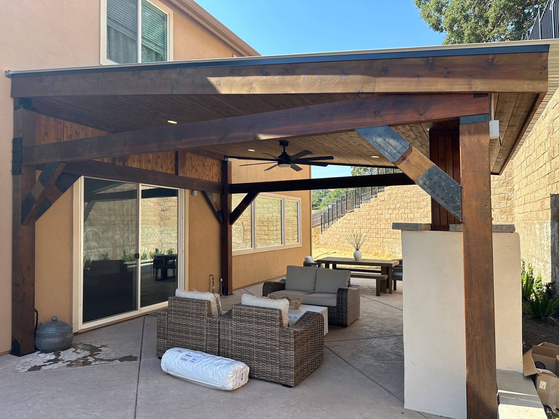 A wooden patio cover and wicker furniture.