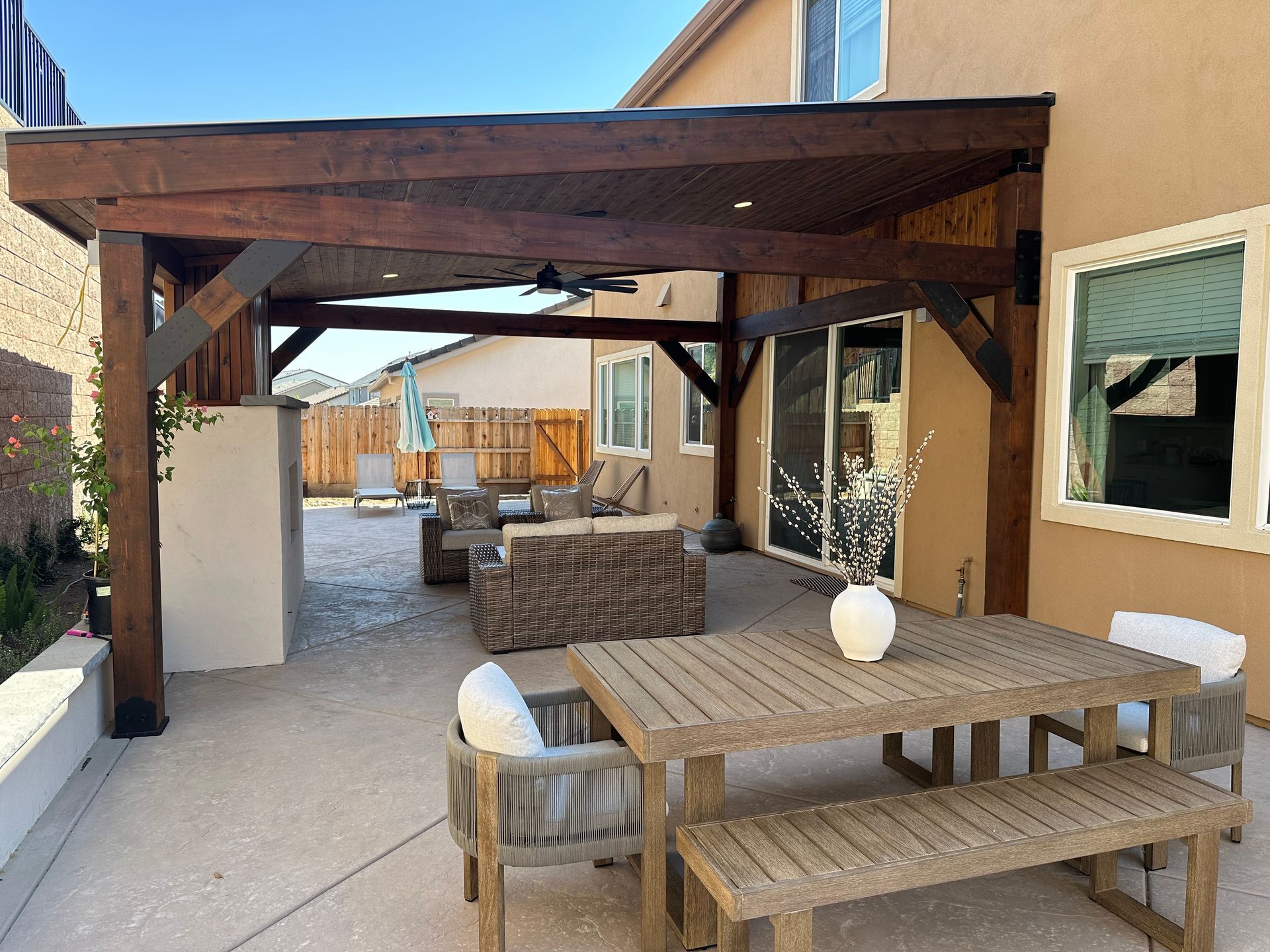 A patio with a table and benches under a pergola
