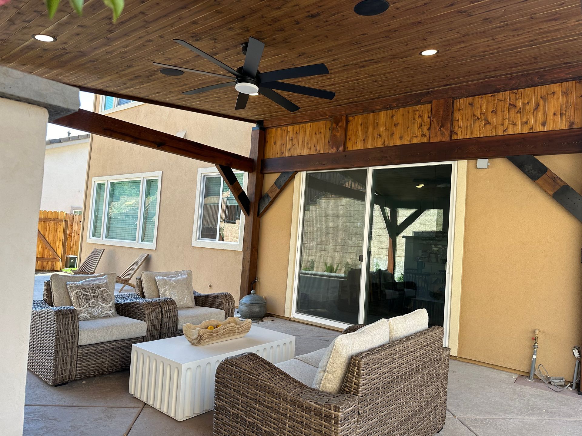 A patio with wicker furniture and a ceiling fan
