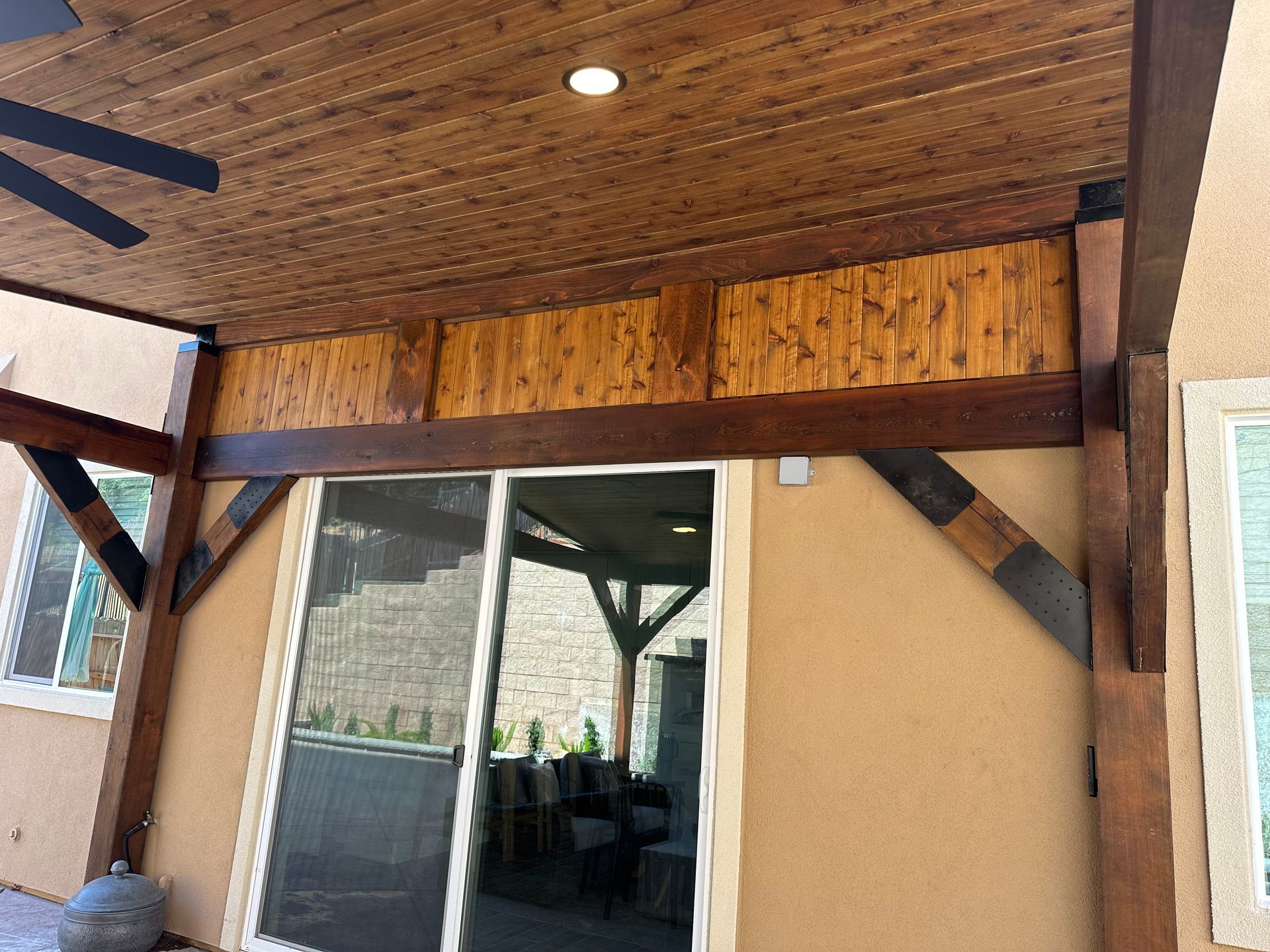 A patio with a wooden ceiling and a sliding glass door.