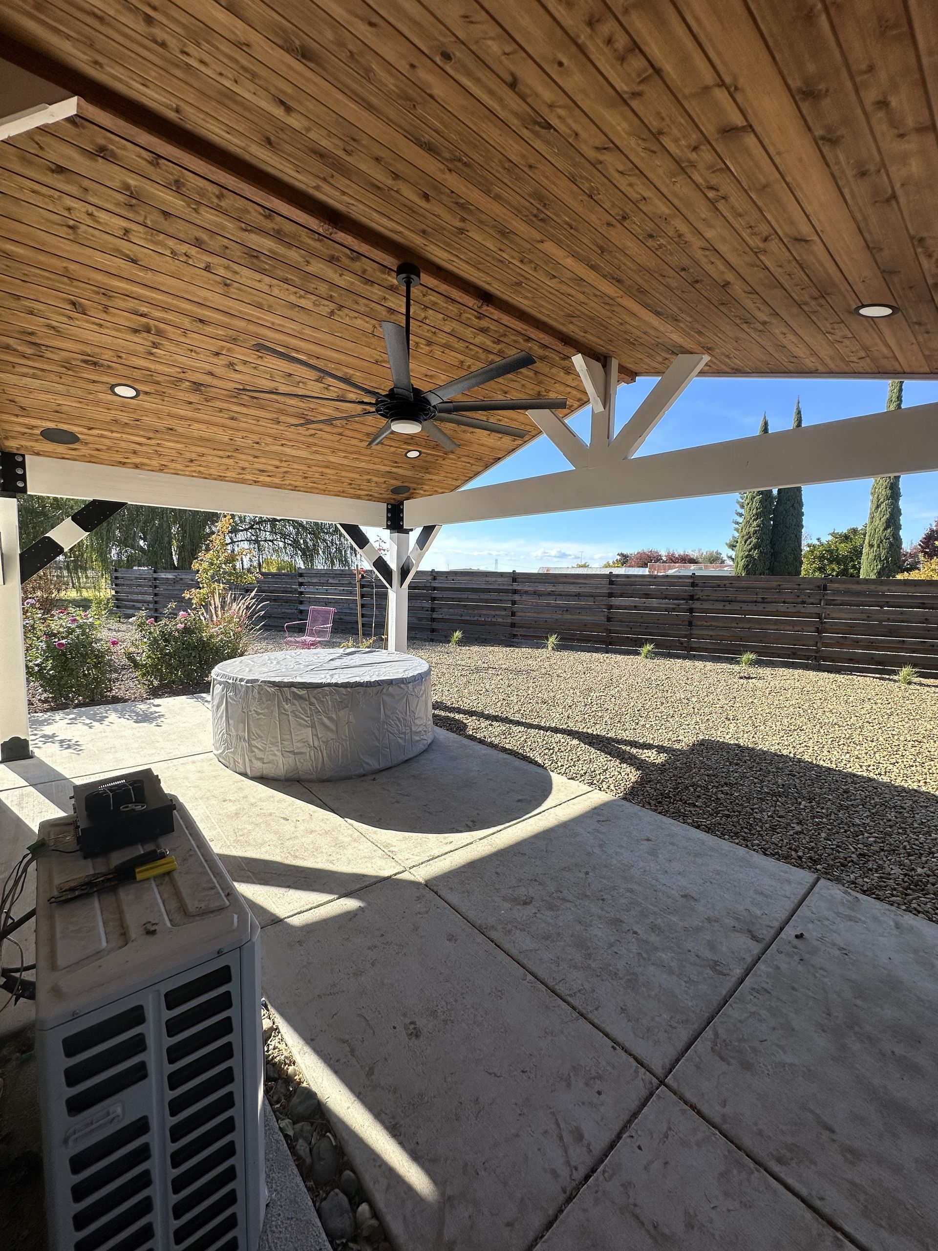 Outdoor patio with a wood ceiling, fan, and a concrete fire pit.