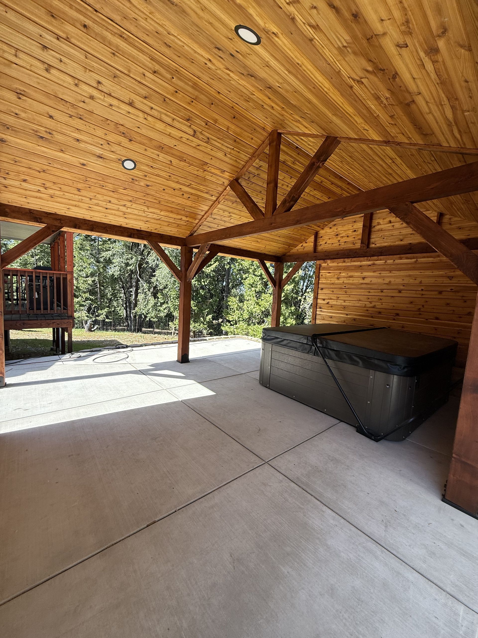 Covered pavilion with wooden beams and hot tub.