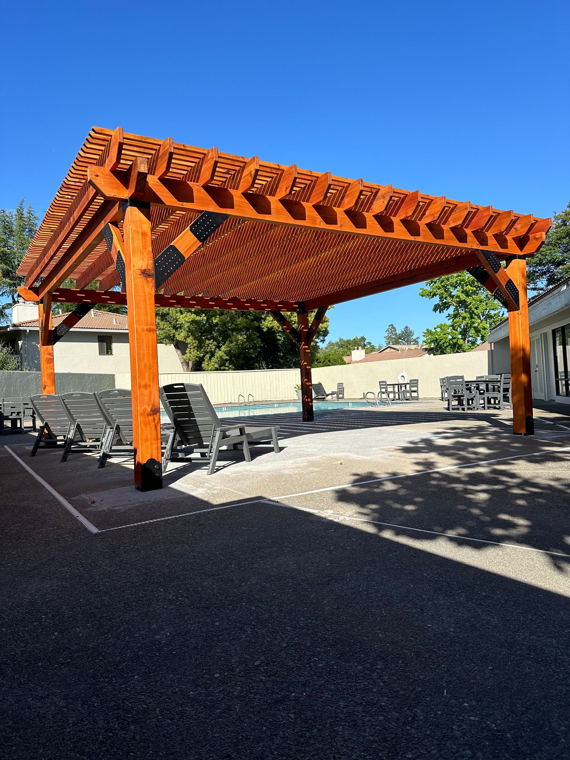 A large wooden pergola over a swimming pool