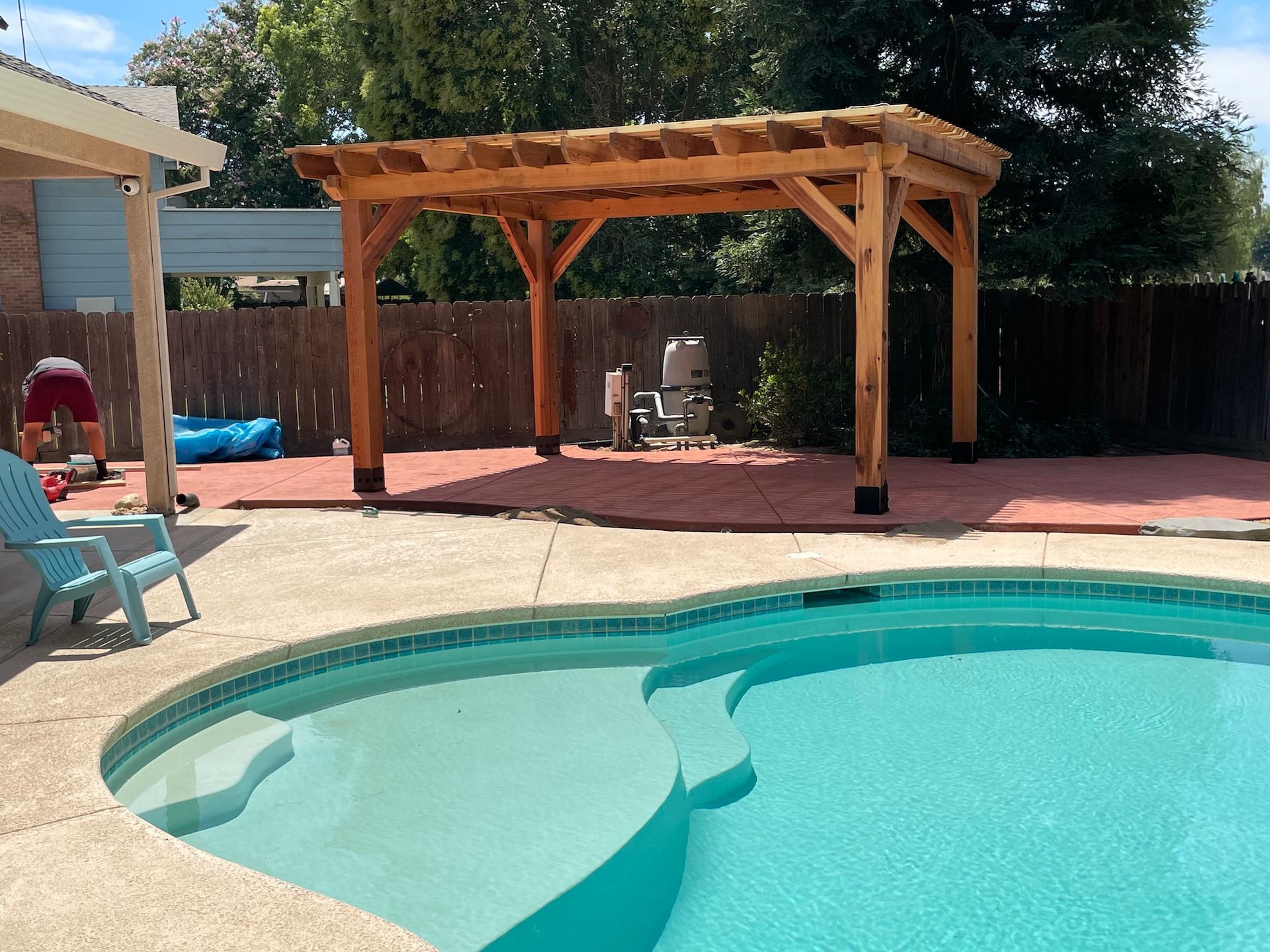 A large swimming pool with a wooden pergola over it