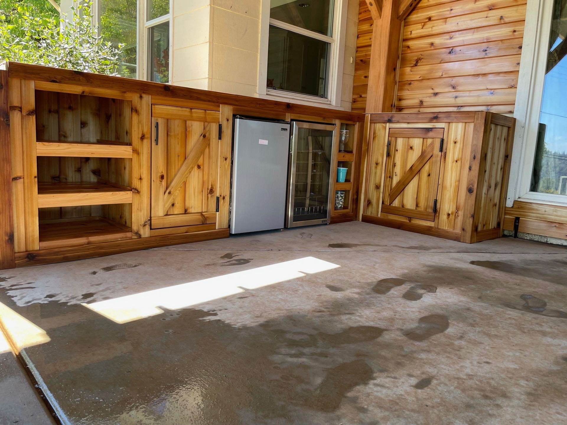 A wooden kitchen with a refrigerator and a stainless steel refrigerator.