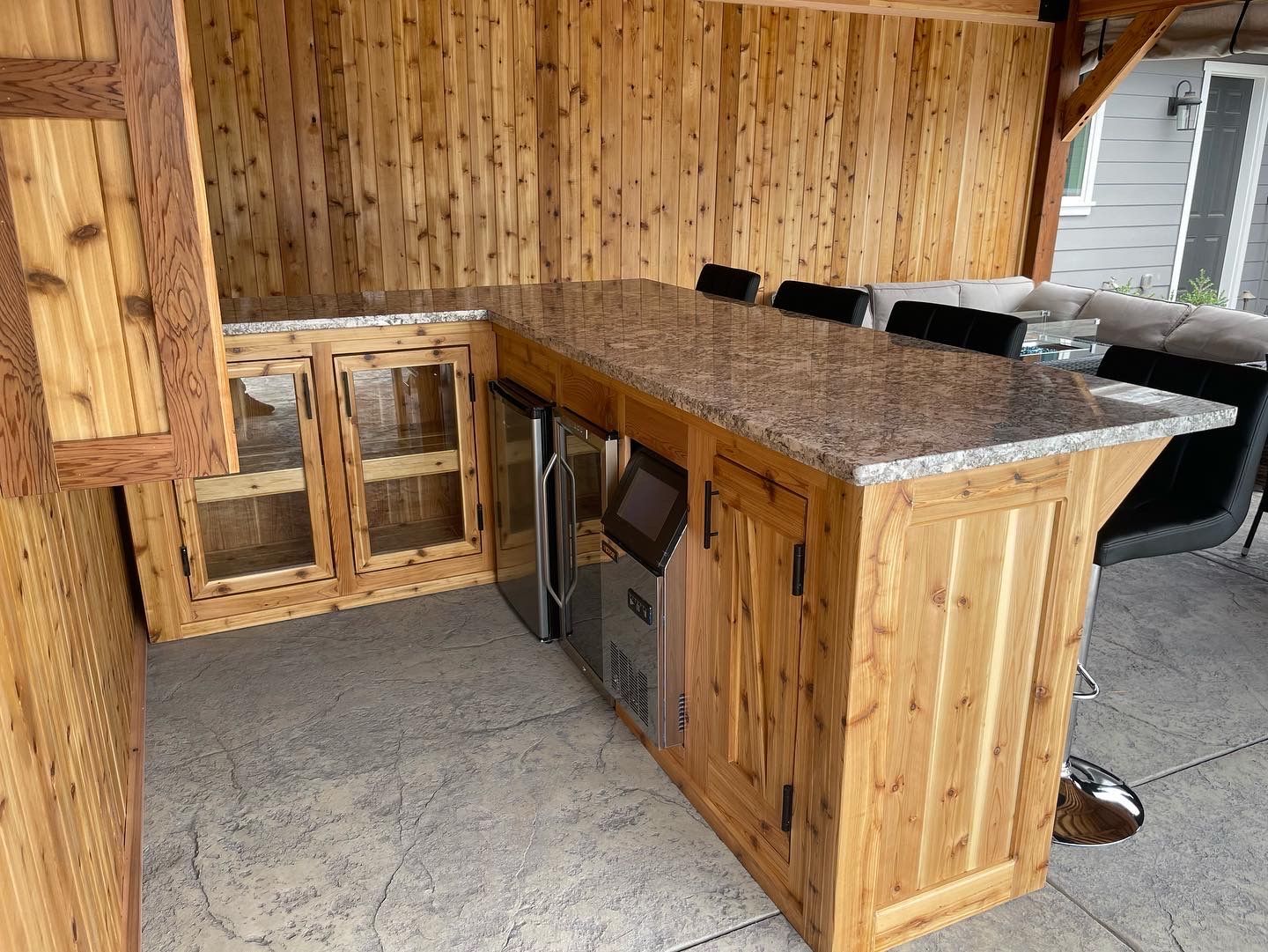 A wooden kitchen with a granite counter top and a refrigerator.