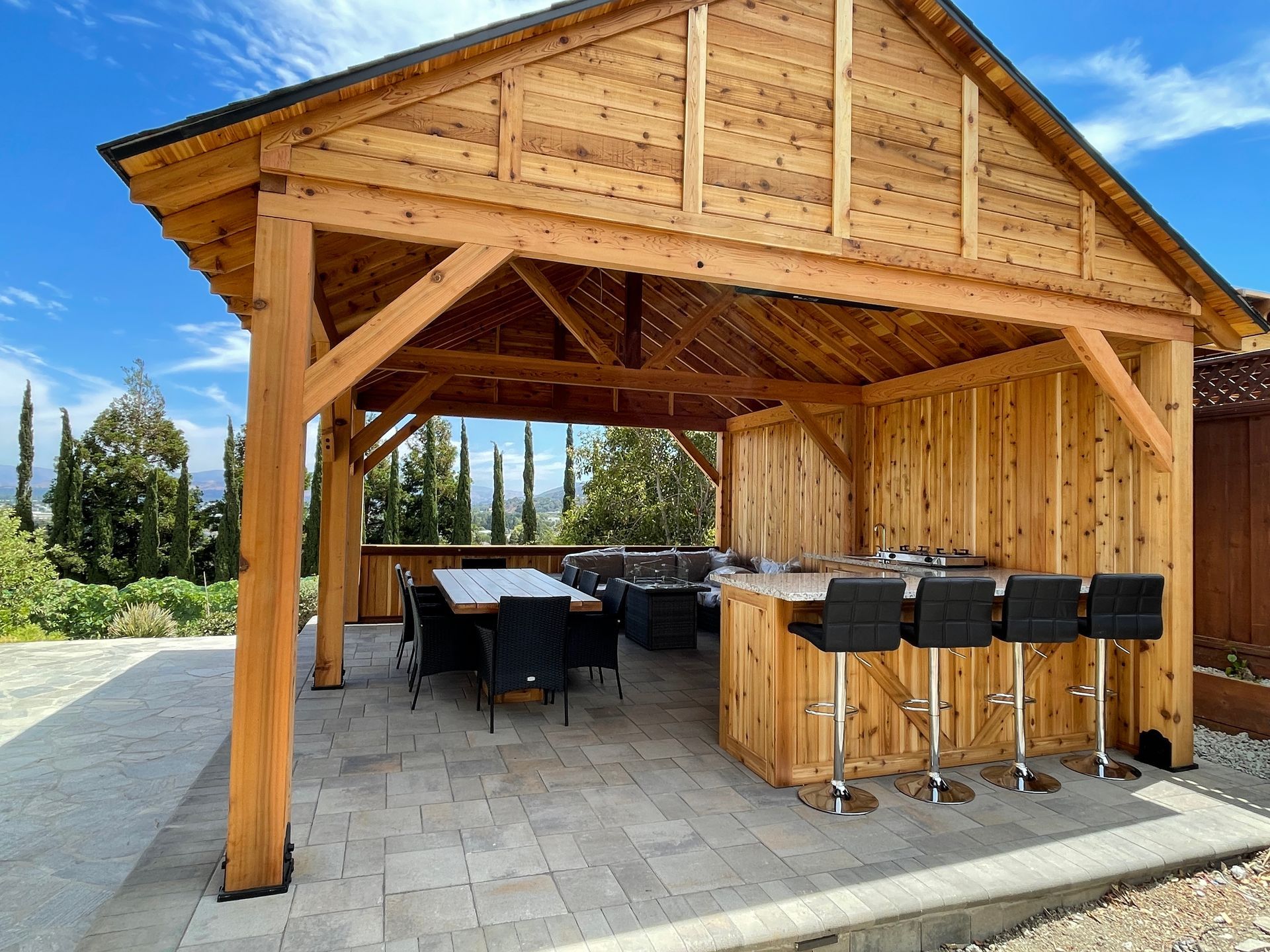 A wooden gazebo with a table and chairs underneath it