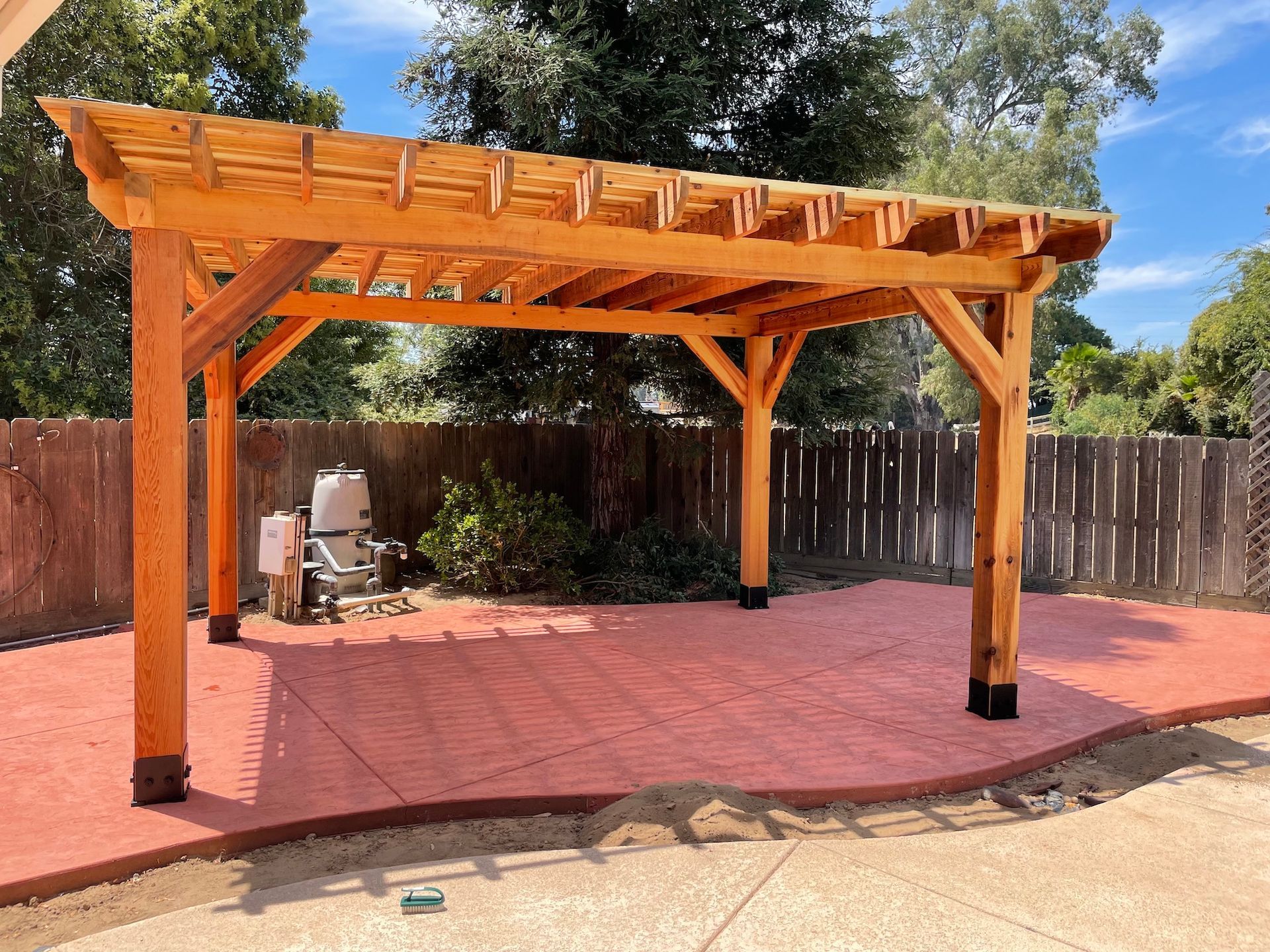 a wooden pergola is sitting on top of a concrete patio in a backyard .