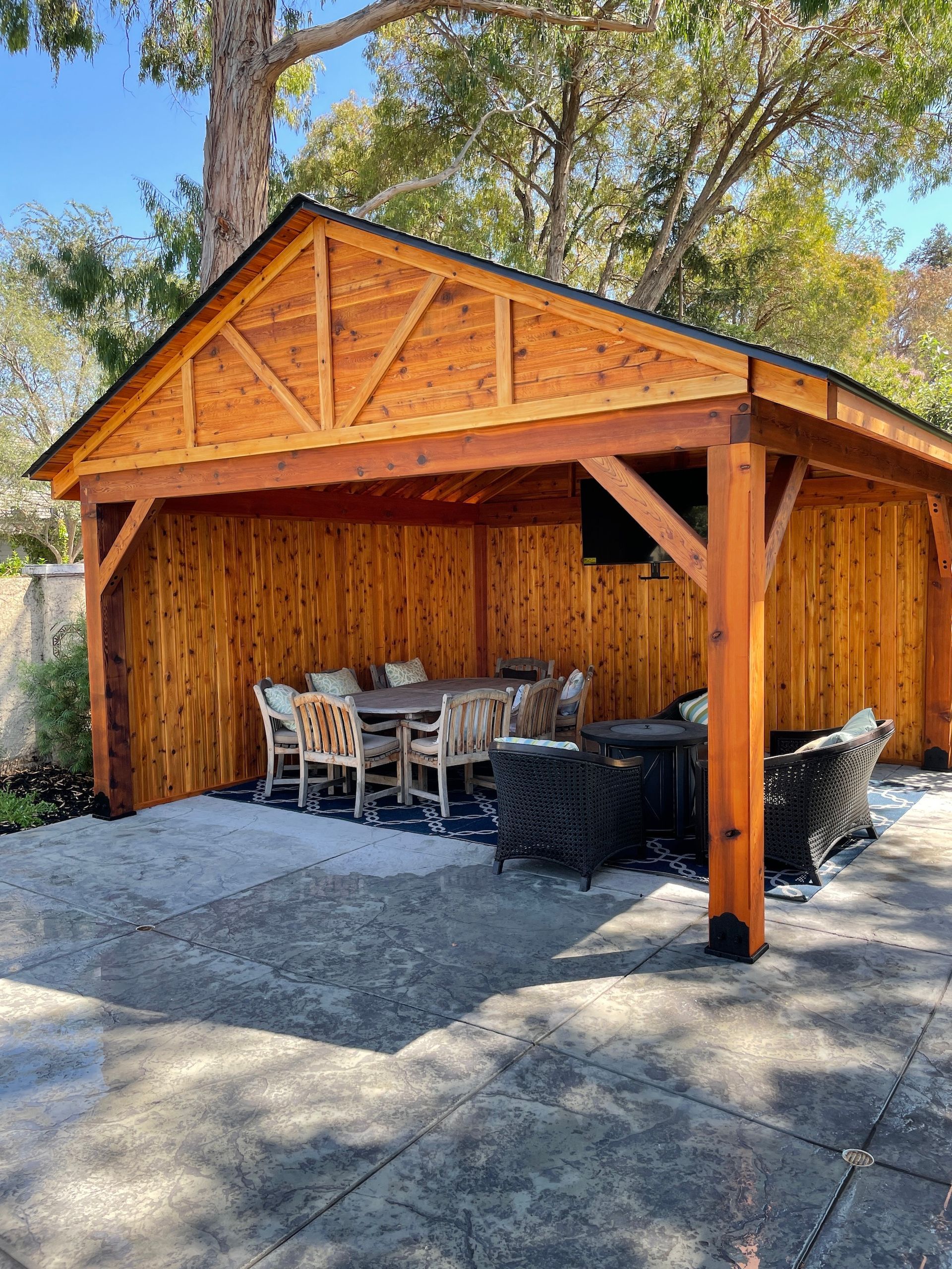A wooden pavilion with a table and chairs underneath it.